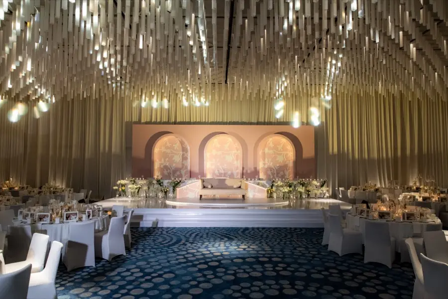 Ballroom with a suspended gold rod ceiling above an arched backdrop